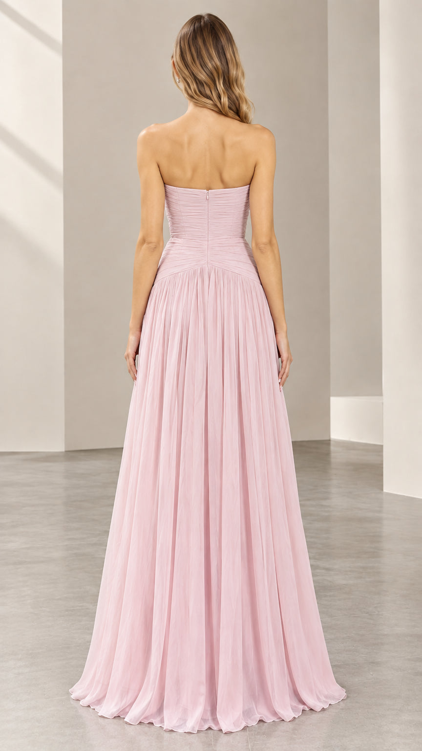 Back view of woman showing the zip-up ruched back and flowing skirt of blush pink gown