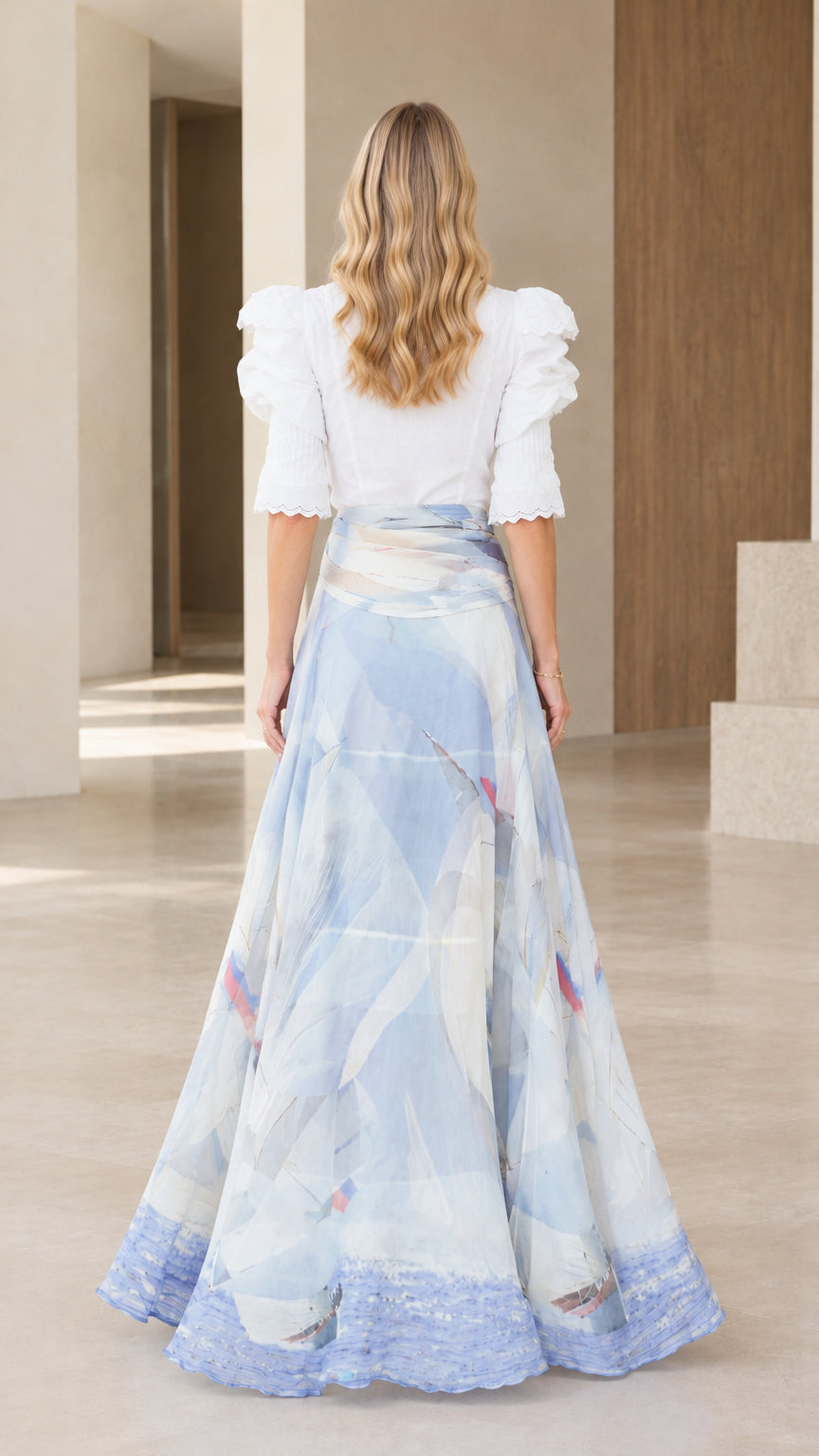 Back view of woman wearing white high-neck puff sleeve blouse and sky blue abstract maxi skirt
