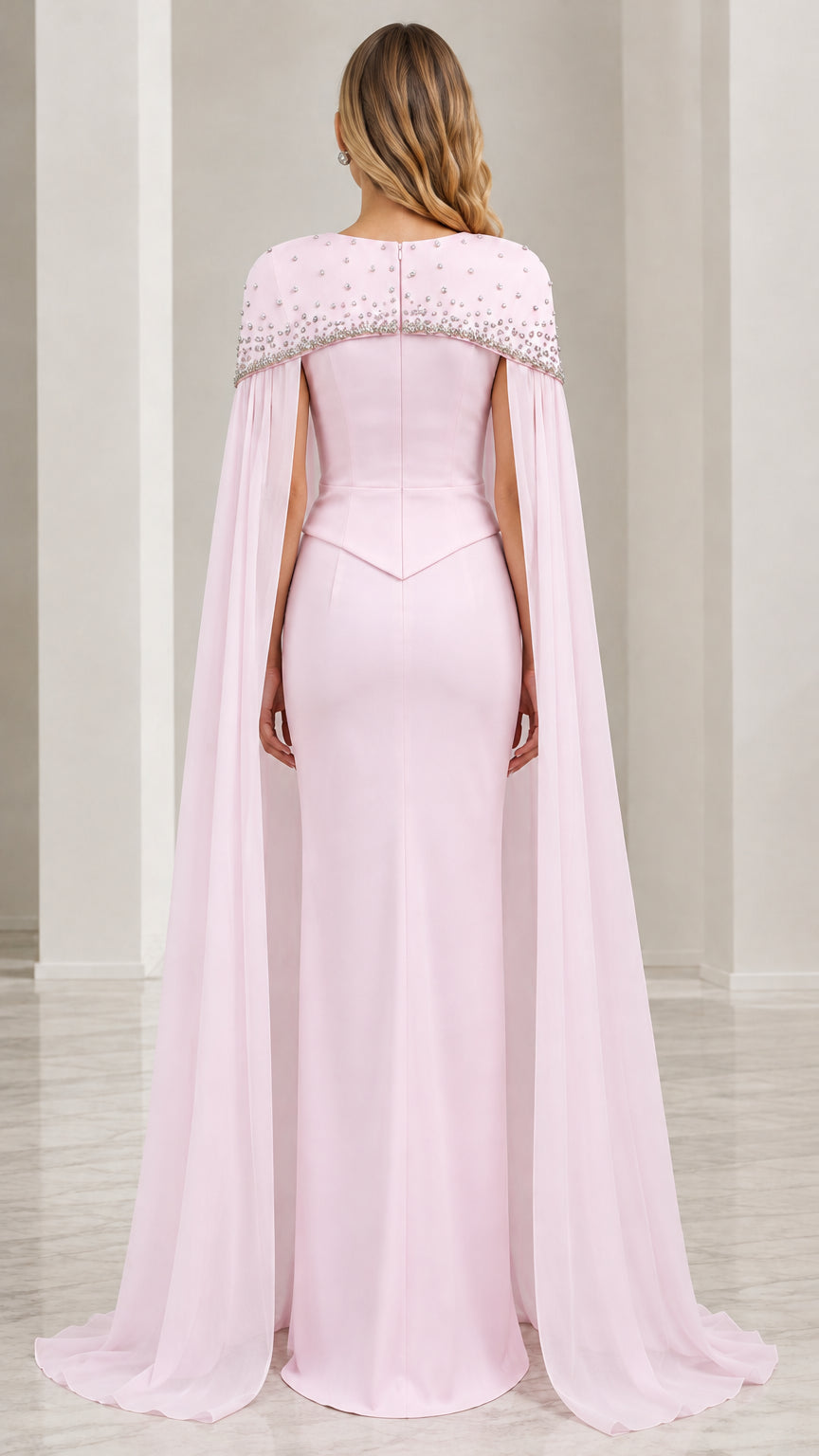 Back view of model in blush pink formal gown with long cape overlay