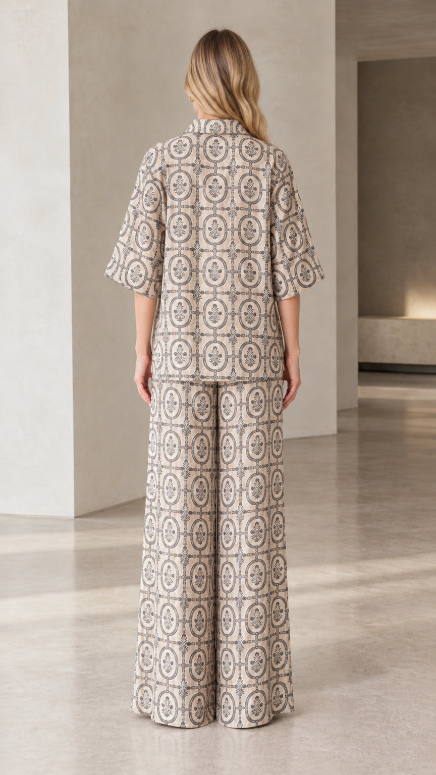 Back view of woman wearing beige printed button-down top and wide-leg trousers