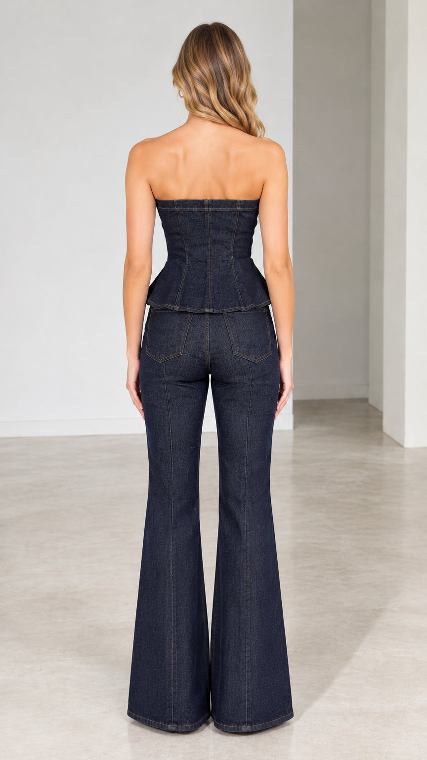 Model wearing dark blue strapless denim set, back view showing smocked corset back and flare trousers