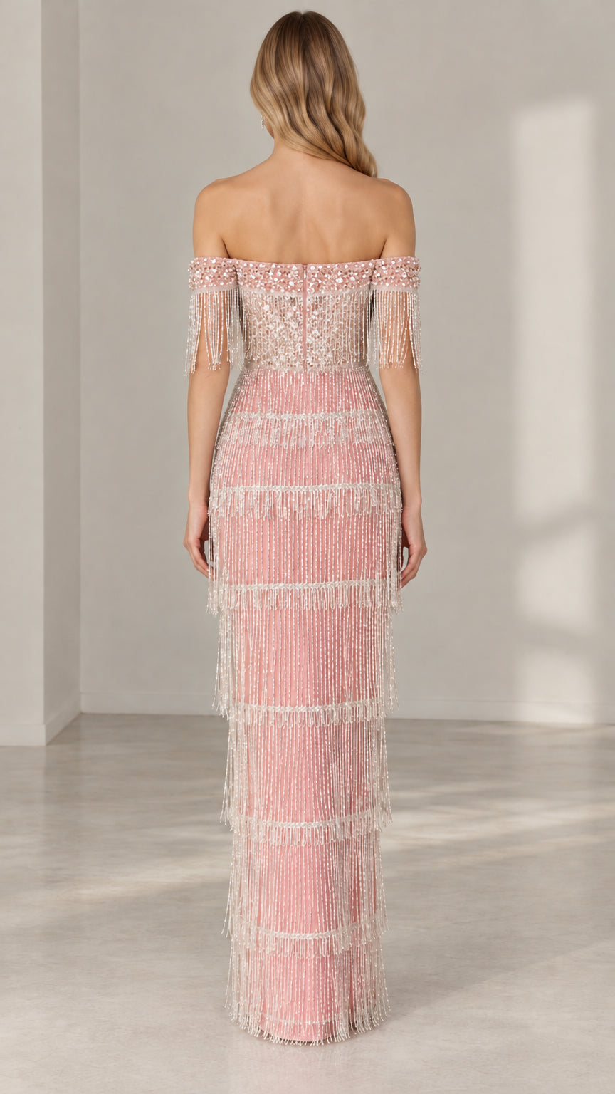 Back view of model showing off-the-shoulder back design of blush pink beaded gown