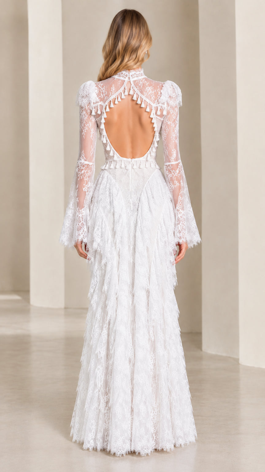 Back view of model in white open back lace evening dress with fringe trim
