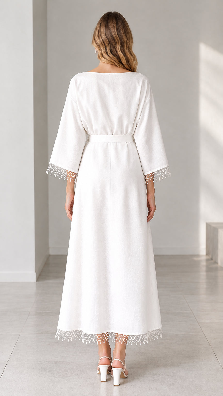 Back view of woman wearing white maxi dress showing clean silhouette and hemline trim