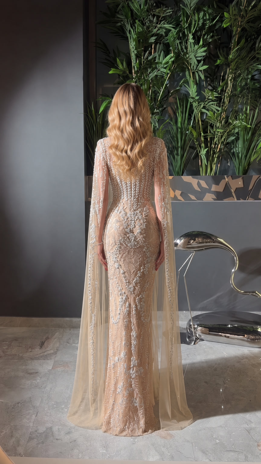 Back view of champagne cape evening gown showing floor-length sheer cape detail