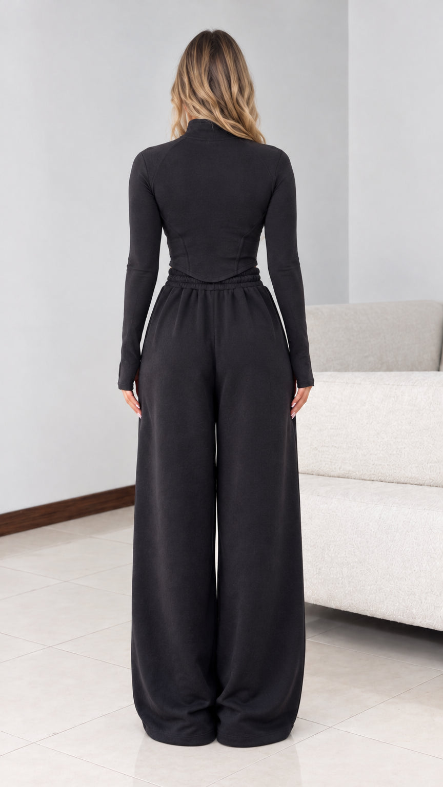 Back view of model wearing black half zip top and wide leg pants