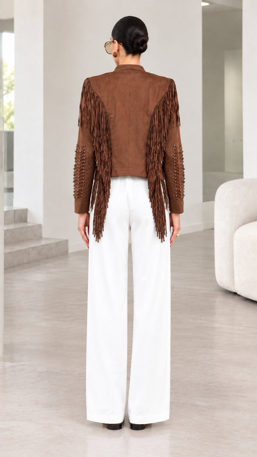 Back view of model showing back yoke fringe detailing on brown jacket