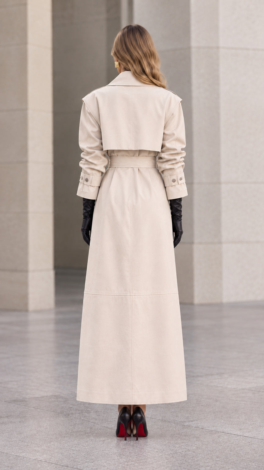 Back view of woman wearing cream maxi trench coat showing back storm flap and vent