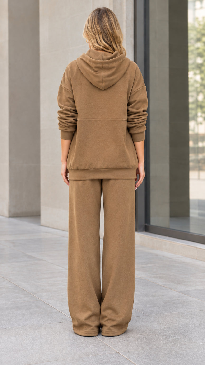 Back view of woman wearing relaxed camel hooded sweatshirt and wide-leg track pants