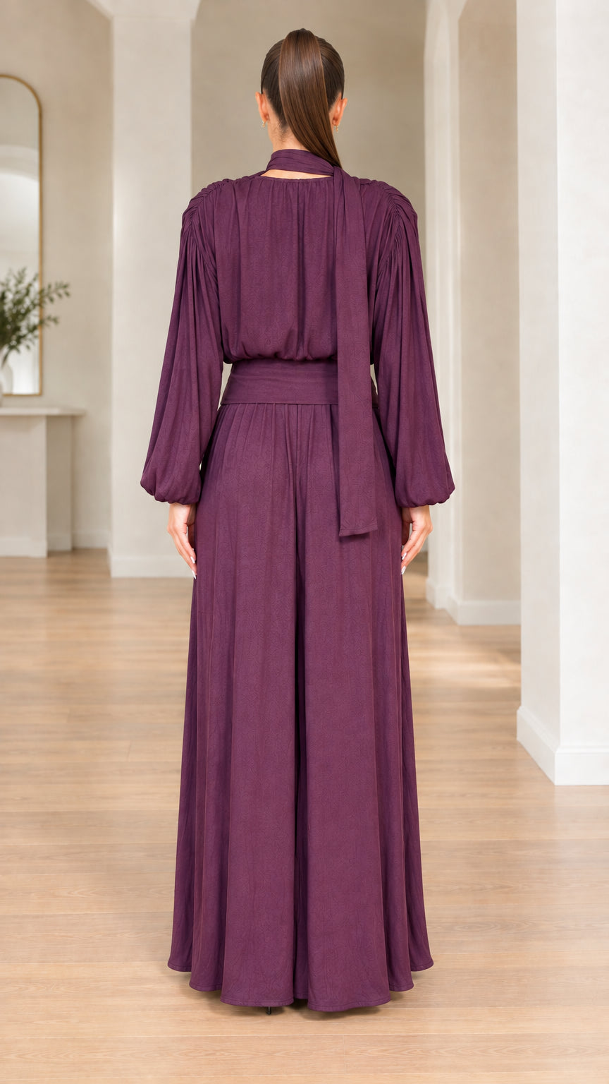 Back view of plum long-sleeve jumpsuit showing trailing neck scarf
