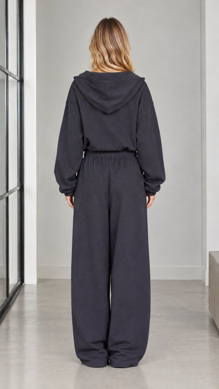 Back view of woman wearing the charcoal hooded jumpsuit with wide-leg pants