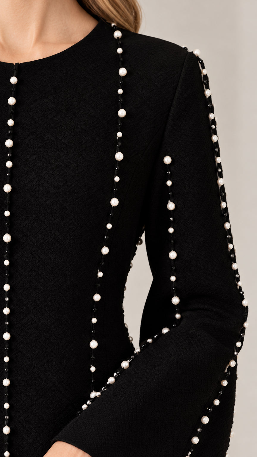 Close-up of pearl bead embellishments along the sleeves and bodice of black dress