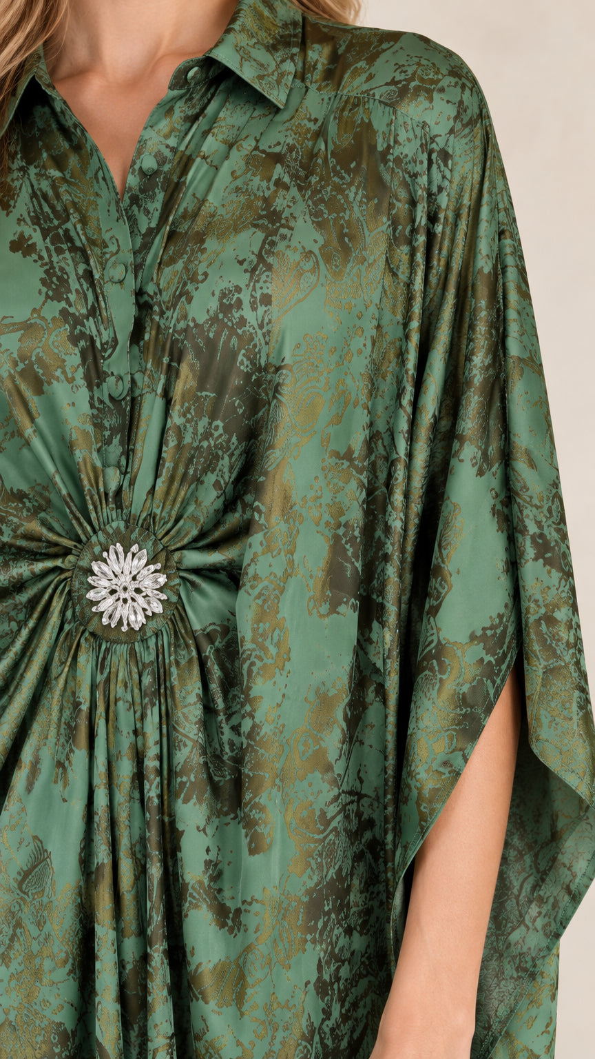 Close-up detail of collared neckline and sparkling crystal waist brooch on green printed kaftan