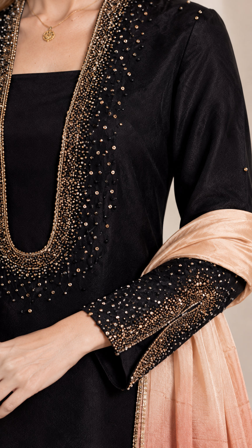 Close-up detail of beaded neckline and cuff embellishments on black dress