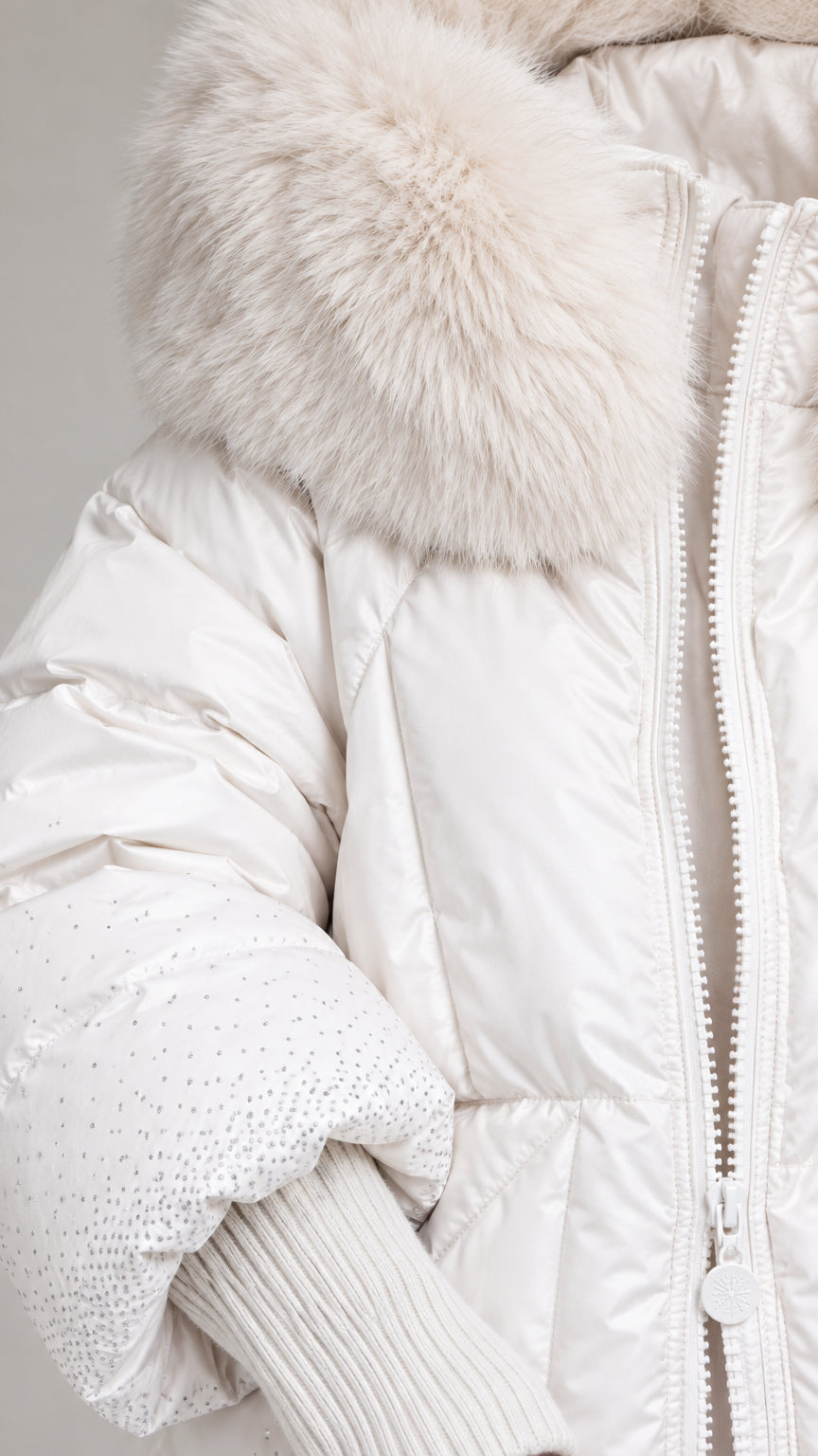 Close-up detail of faux fur hood trim and ribbed cuff with subtle sparkle embellishments on white puffer coat