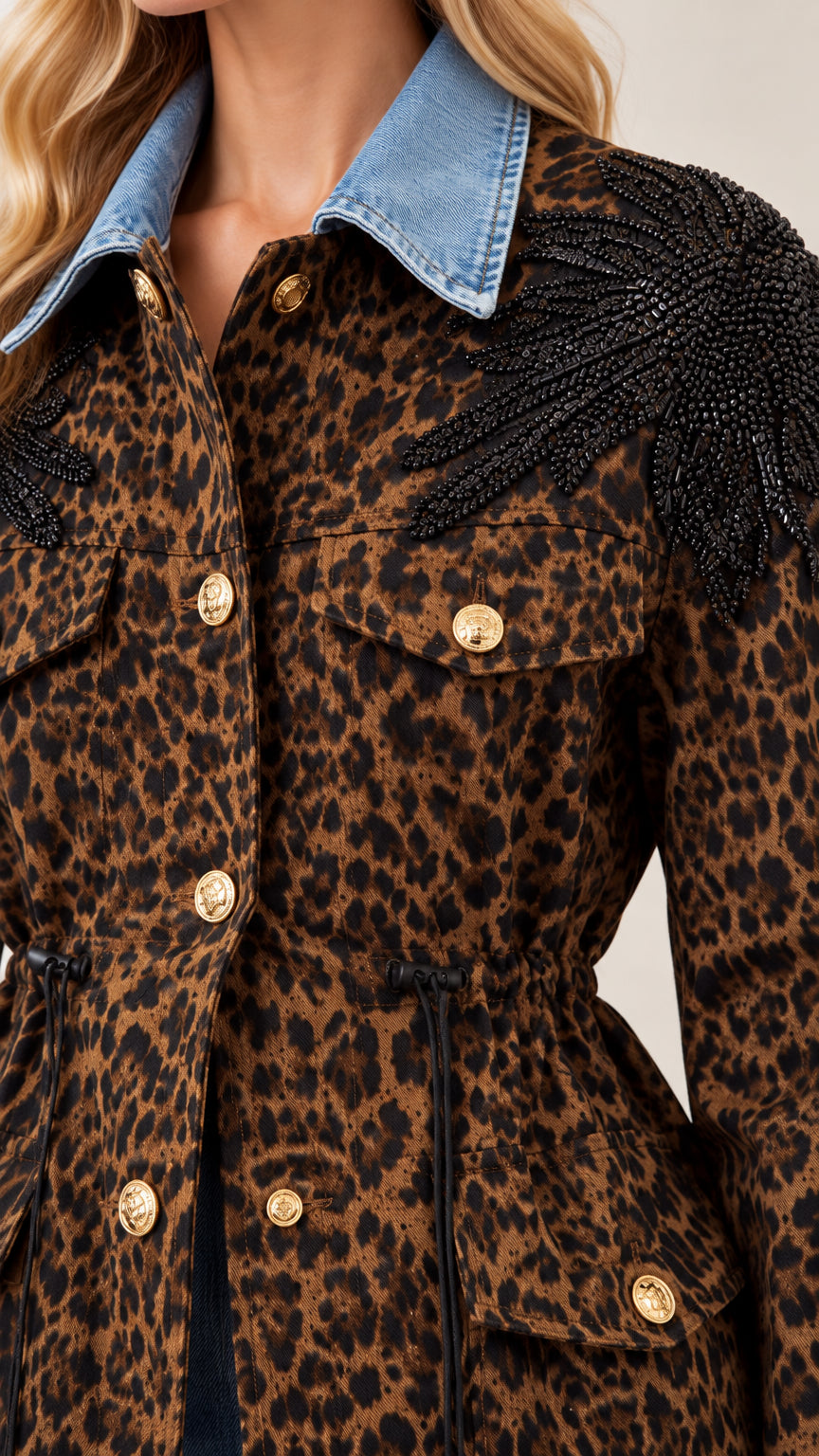 Close-up detail of denim collar, gold buttons, and black beaded shoulder fringe on leopard jacket