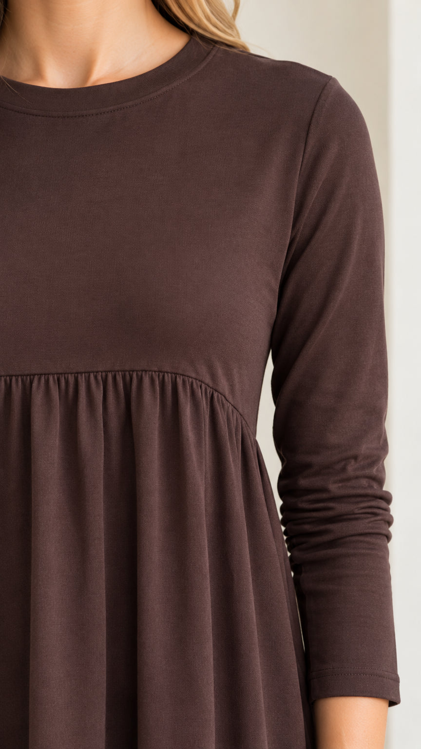 Close-up detail of crew neckline and gathered empire waist seam in chocolate brown