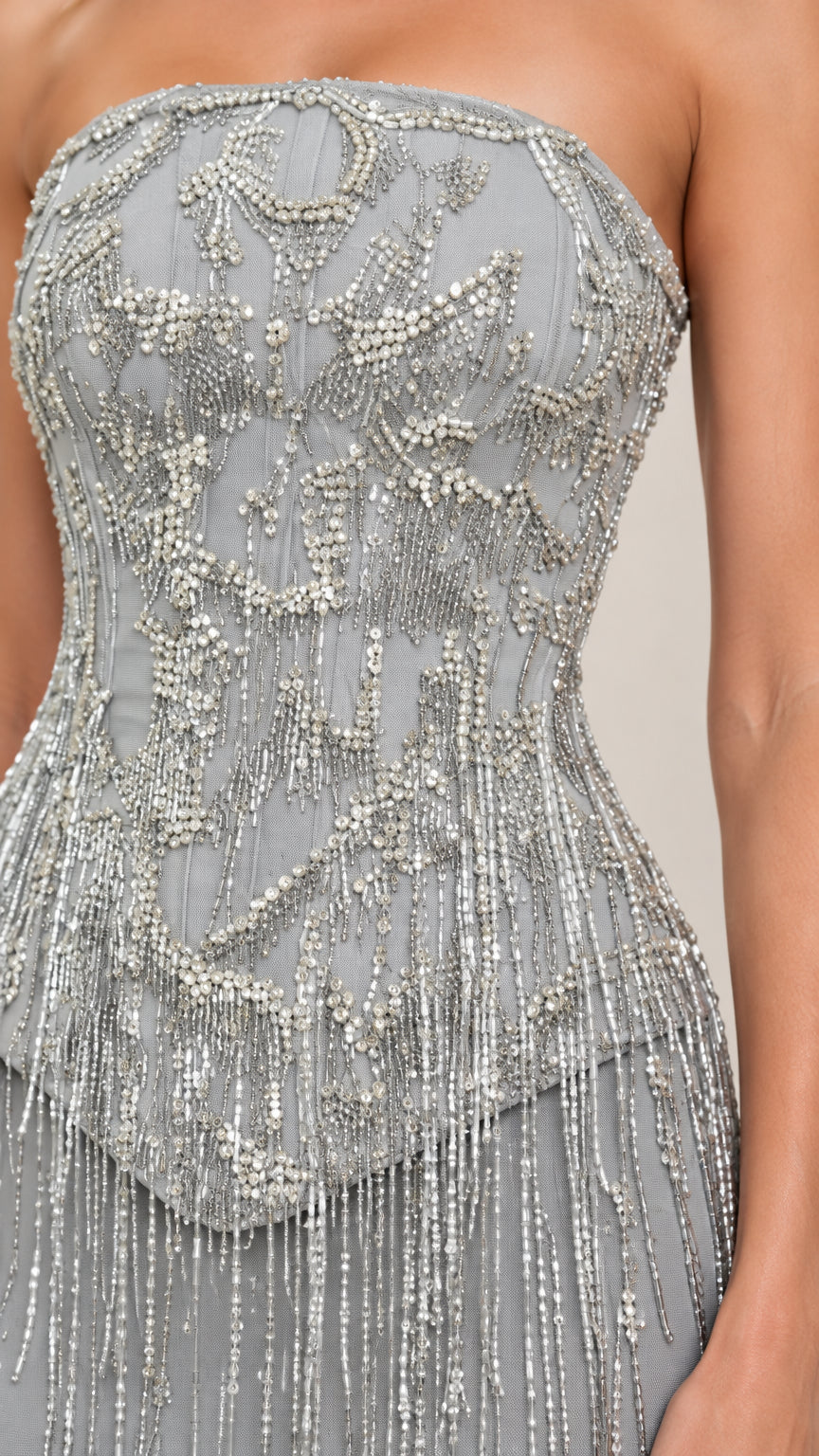 Close-up detail of intricate beadwork and tassel fringe on strapless bodice