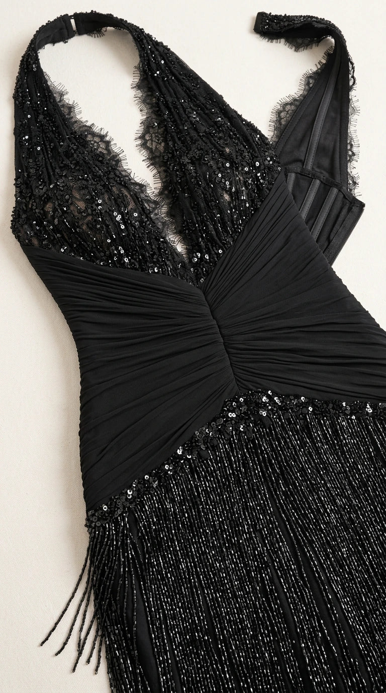 Close-up flat lay of black sequin halter neckline, ruched waist, and fringe detail