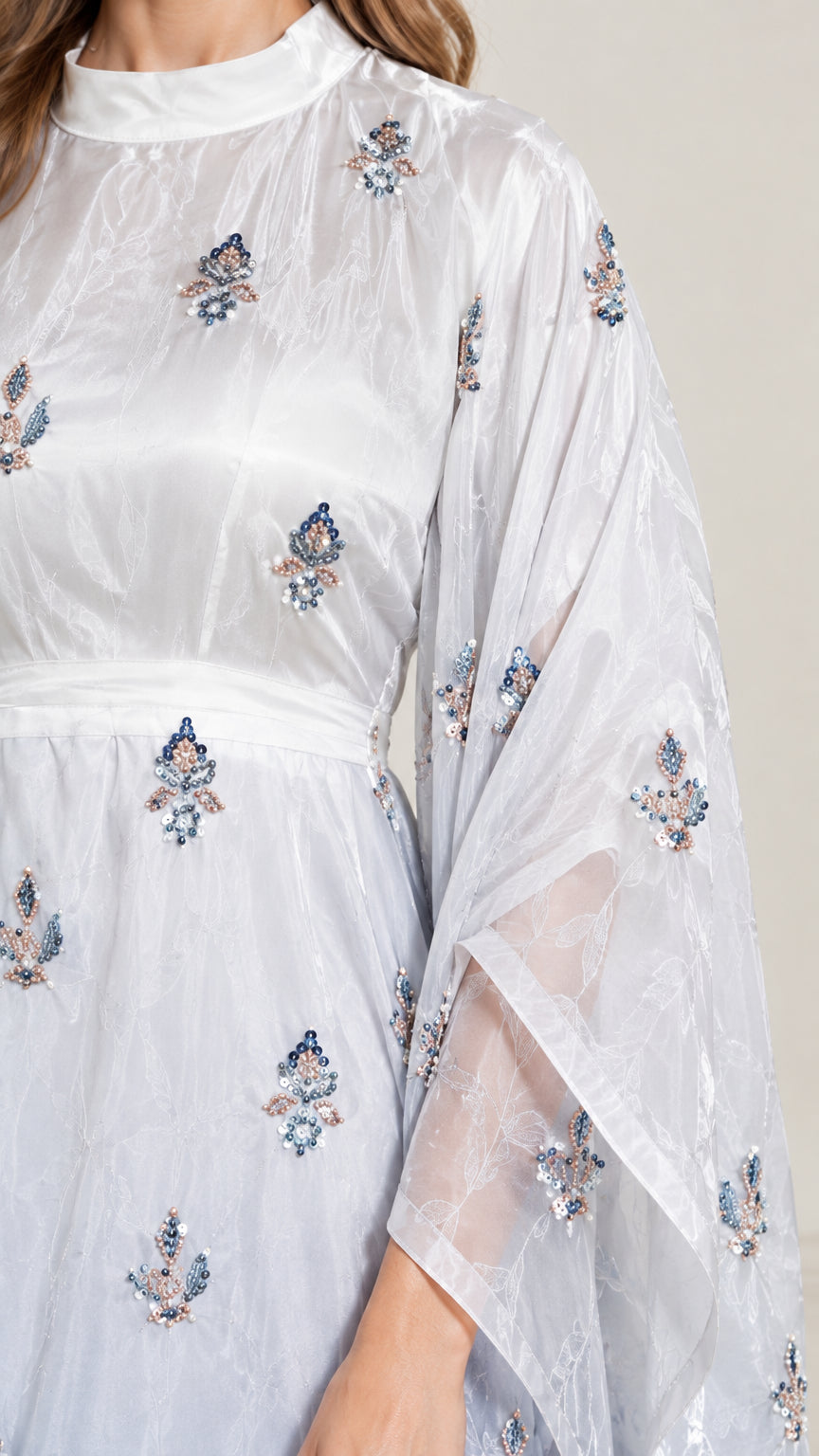 Close-up detail of sheer fabric and delicate floral embroidery on neckline and sleeve