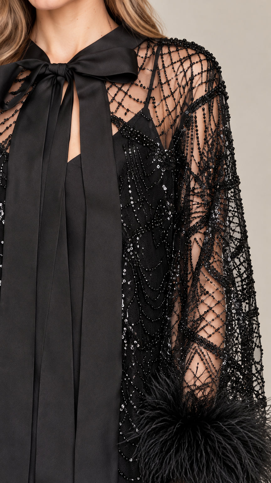 Close-up detail of black bow neckline, beaded mesh, and feather cuff trim