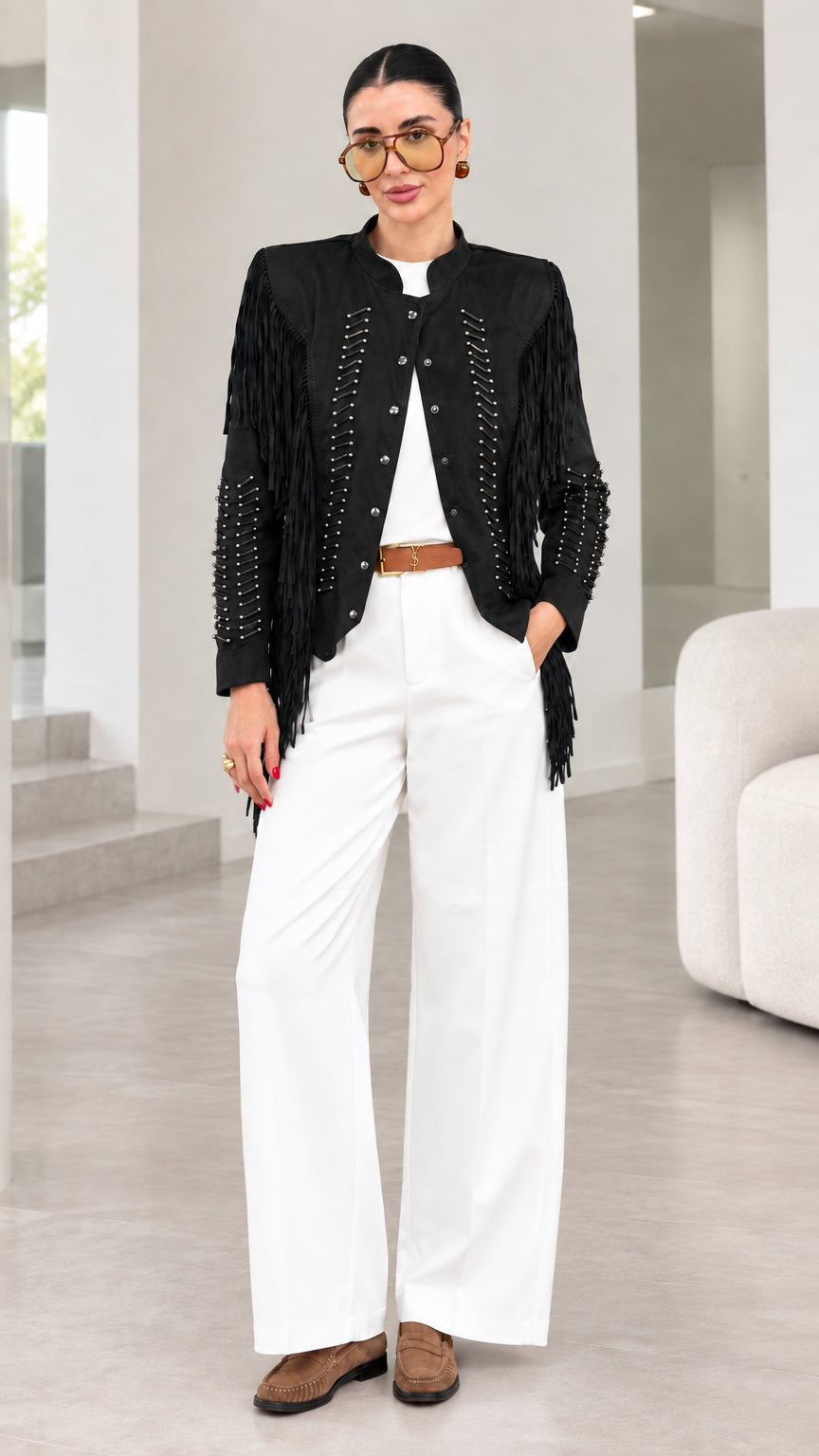 Model wearing black faux suede fringe jacket with white pants