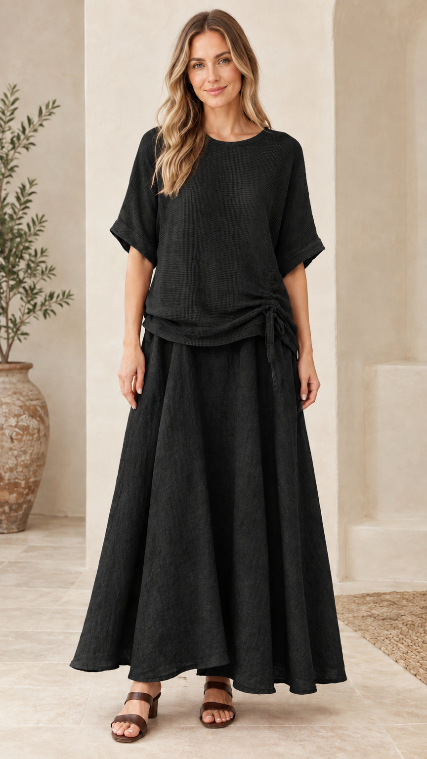Front view of woman wearing black textured two-piece top and maxi skirt outfit