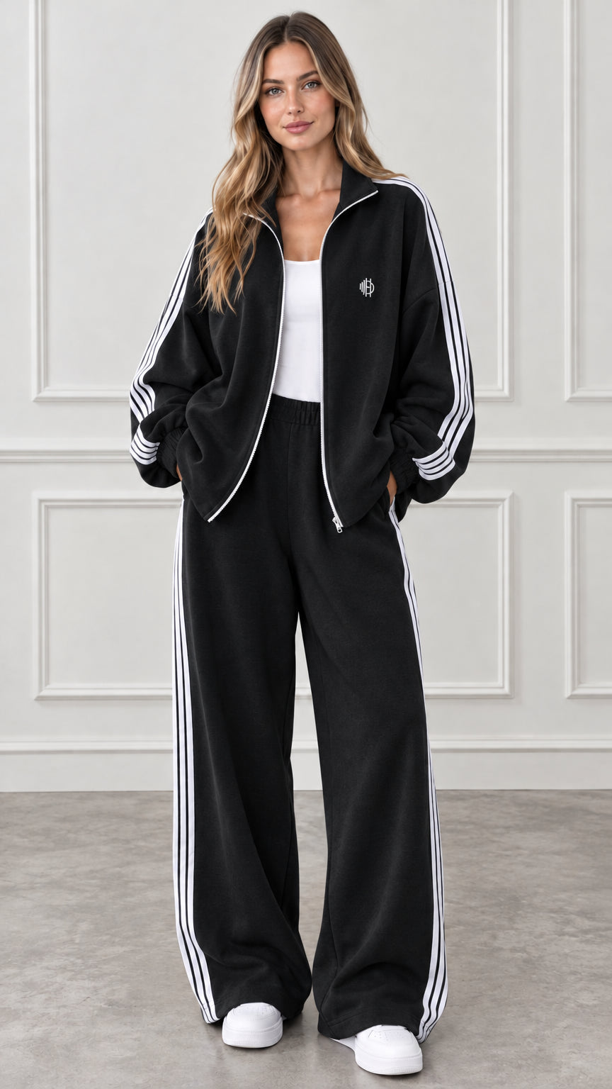 Full-body view of woman wearing black two-piece tracksuit with white side stripes