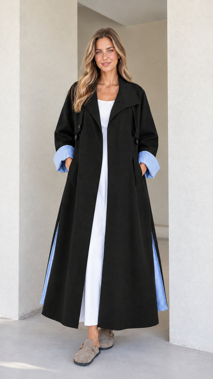 Model wearing the maxi trench duster in classic black with blue striped cuffs