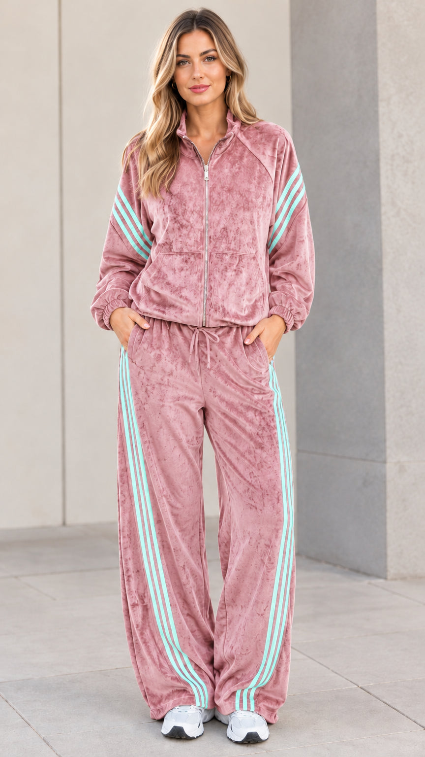 Model wearing dusty pink velour tracksuit set with contrast stripes