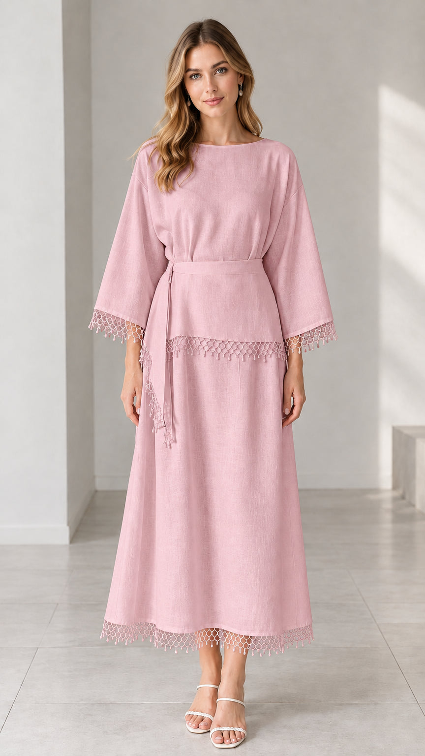 Full-length studio view of woman wearing dusty pink crochet trim belted maxi dress