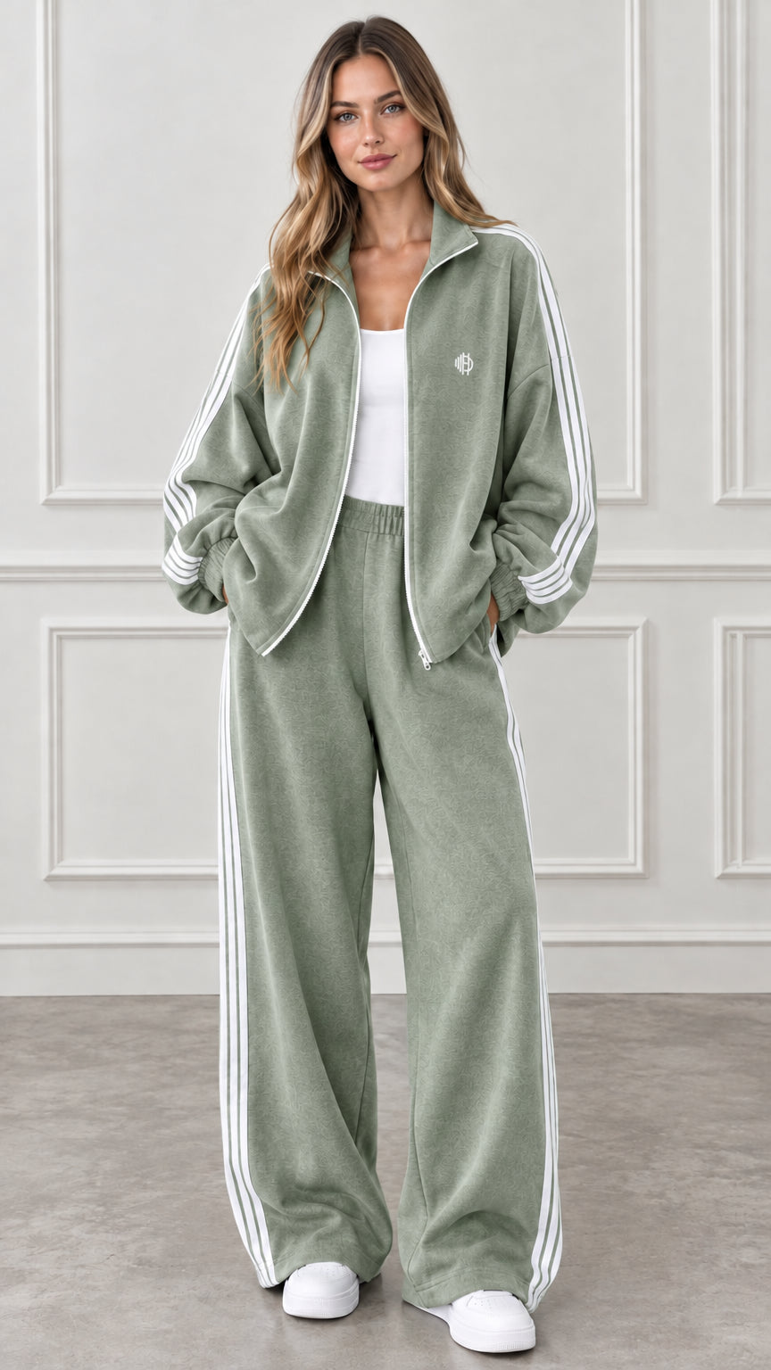 Full-body view of woman wearing sage green two-piece tracksuit with white side stripes