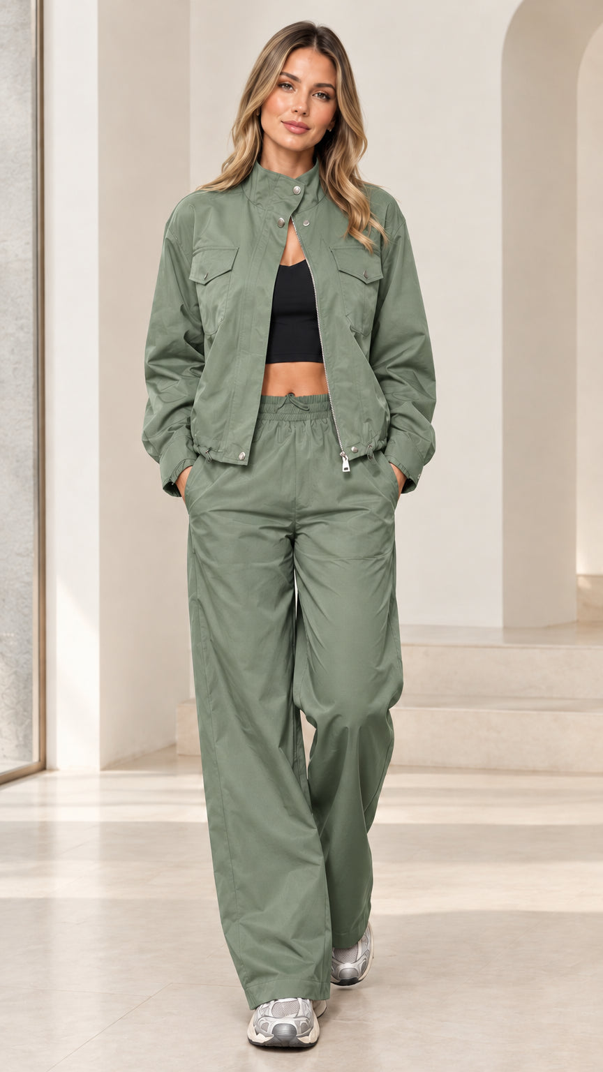 Full-length studio shot of woman wearing sage green zip-up windbreaker track set