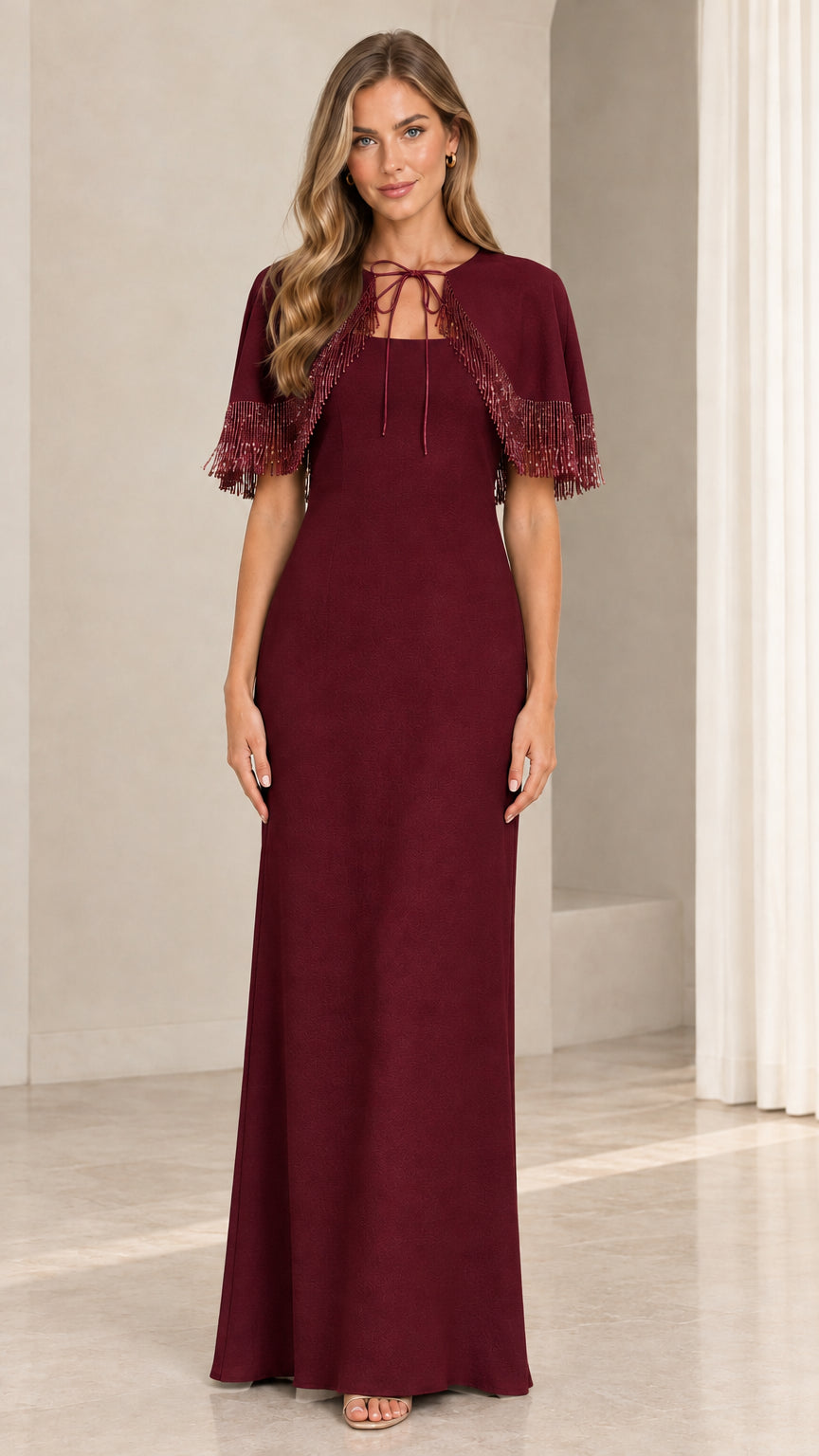 Model wearing burgundy wine red evening dress with fringe trim capelet