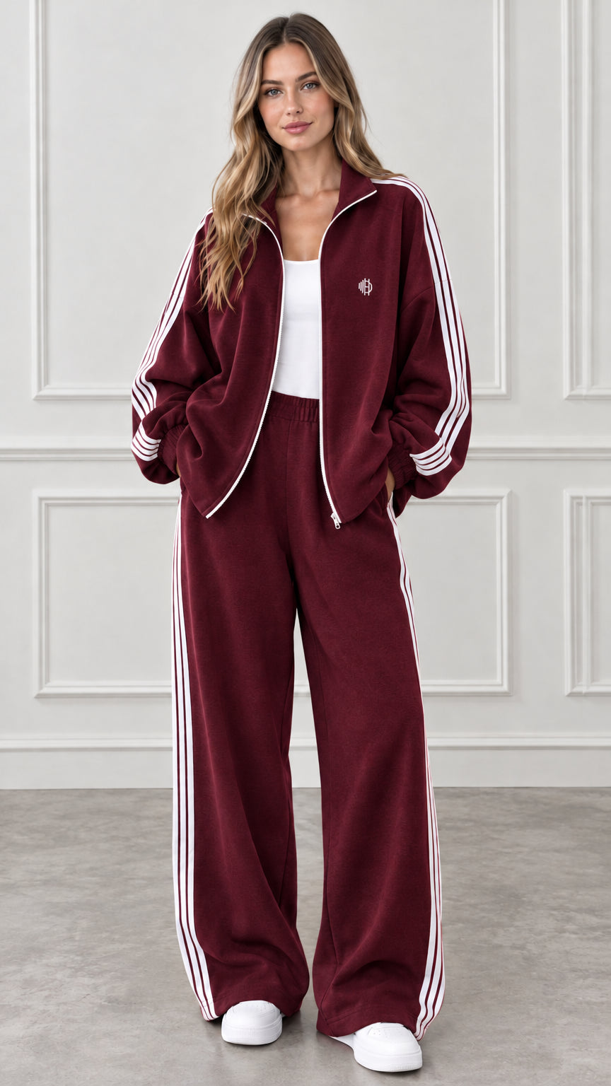 Full-body view of woman wearing burgundy two-piece tracksuit with white side stripes