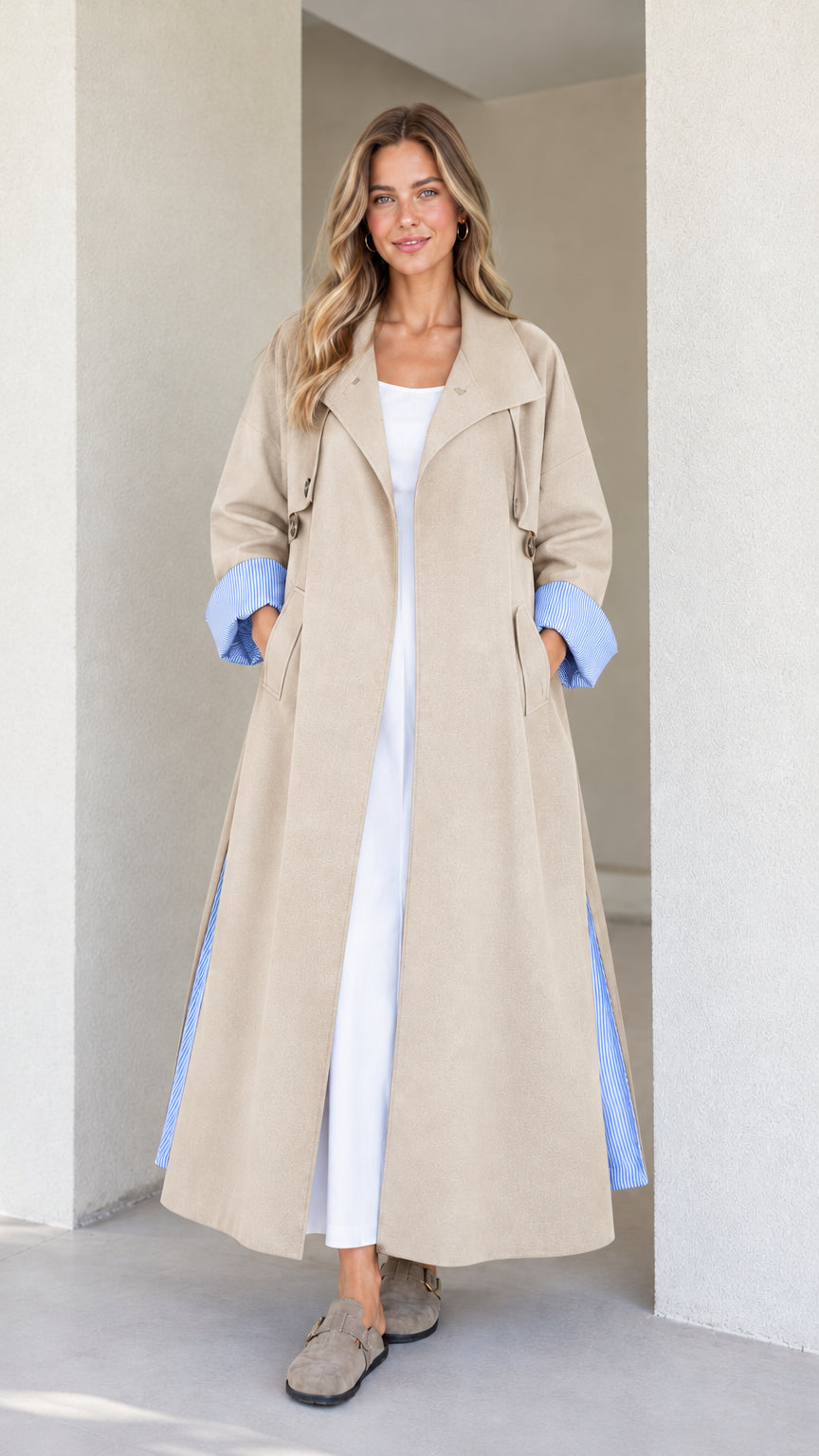 Model wearing the maxi trench duster in neutral beige with blue striped turn-up cuffs